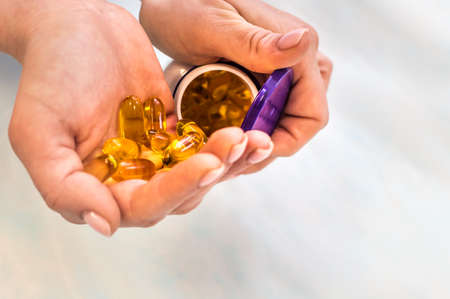Woman holding a jar of omega 3 vitamins in her hands close upの写真素材