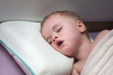 Portrait of a kid sleeping in a bed on a pillowの写真素材