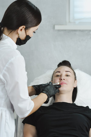 woman enlarges her lips with hyaluronic acid from a cosmetologist. Injection cosmetology. Lip fillersの写真素材