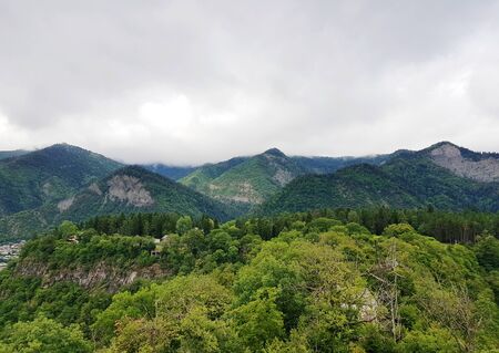 Mountains covered with dense forests under a cloudy sky in Borjomi, Georgiaの写真素材
