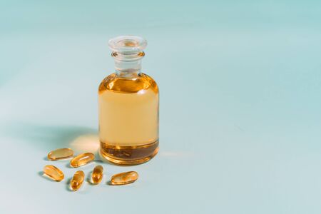 Omega 3 gel capsules. Fish oil pills. Healthy omega-3 and bottle of oil on blue table.の写真素材