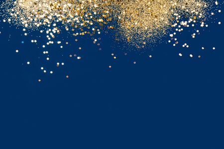 Festive gold confetti on classic blue background.の写真素材
