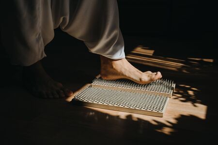 Close-up of man on bed of nails at morning yoga practice.の写真素材