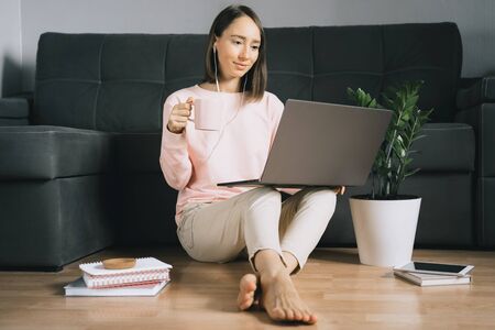 Young woman sitting on the floor and using laptop.の写真素材