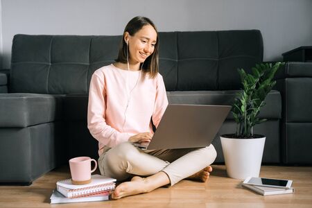 Young woman sitting on the floor and using laptop.の写真素材