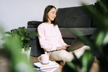 Young woman sitting on the floor and using laptop.の写真素材
