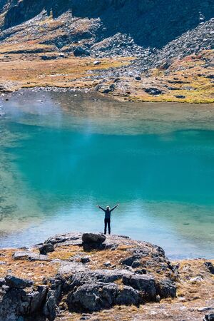 Adult travel girl staying back to camera on top of high rock cape near lake and enjoy by beautiful landscape summer view in Altai, Russia.の写真素材