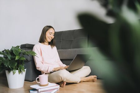 Young woman sitting on the floor and using laptop.の写真素材