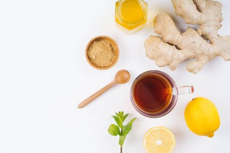 A glass cup of natural tea with ginger, lemon, mint and honey on white background.の写真素材