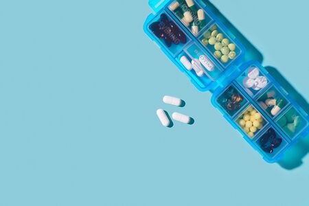 Prescription pills and vitamins in a blue pill box on neo mint color background. Flat lay photo, space for text.の写真素材