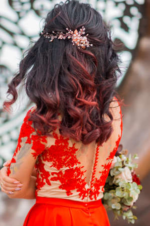 The bride in red dress from the back. Wedding hairstyle with barretteの写真素材