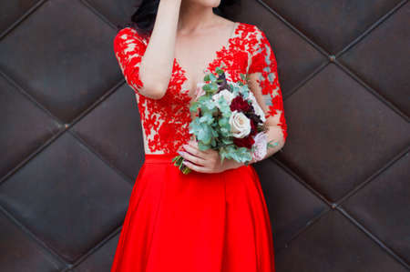 Close up of bride in red wedding dress and bridal bouquet of rosesの写真素材