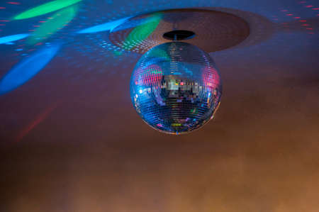 The silver disco ball with violet, green and blue lightsの写真素材