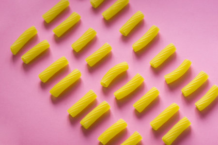 Italian food concept. Pasta Tortiglioni on pink background