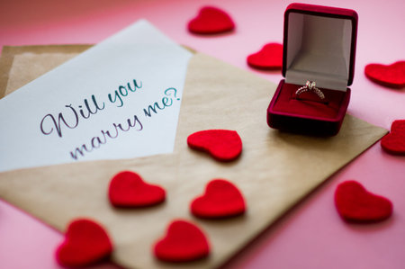 Beautiful wedding ring with precious stone in a red gift box, carved hearts and envelope with a note...