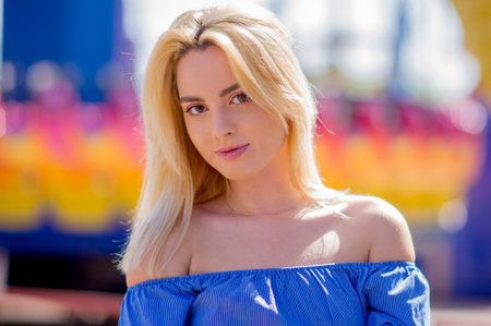 Portrait of a beautiful young woman with blond hair and a serious look on a bright background