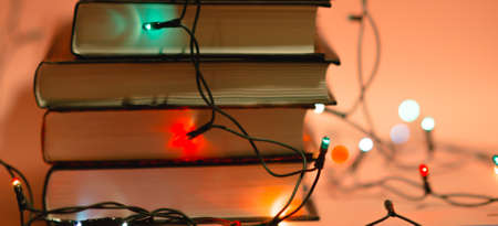 Stack of books and 
garland on pink background. Reading for girls concept. Decoration for cozy interior. Long wide bannerの写真素材