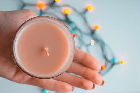 Aromatic candle in the hand and garland on the backgroundの写真素材