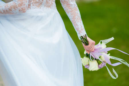 Bride in a white dress holds a wedding bouquetの写真素材