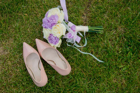 Shoes and wedding bouquet on the grassの写真素材