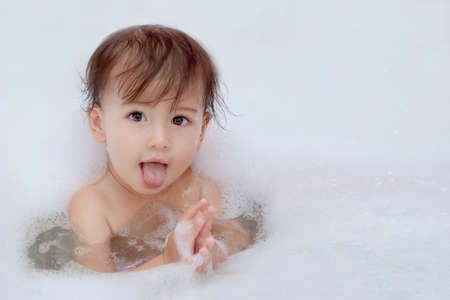 funny cute baby is swimming in bath and shows languageの写真素材