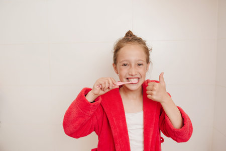 The joyful girl brushes teeth in a bathroom