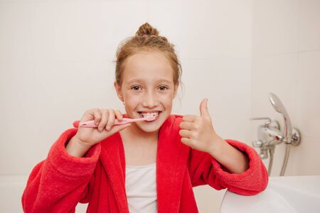 The joyful girl brushes teeth in a bathroomの写真素材