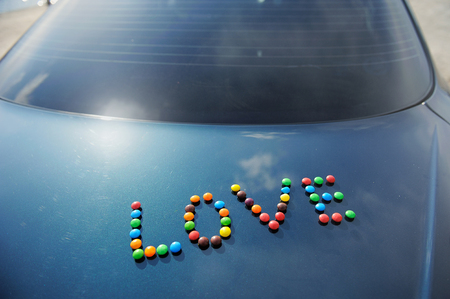 The word Love is collected from multi-colored candies against the background of the dark blue carの写真素材