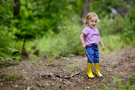 The little lovely girl walks on the wood. The girl spends time in the fresh air