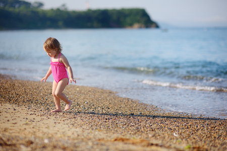 The little girl runs on the beach at the seashoreの写真素材
