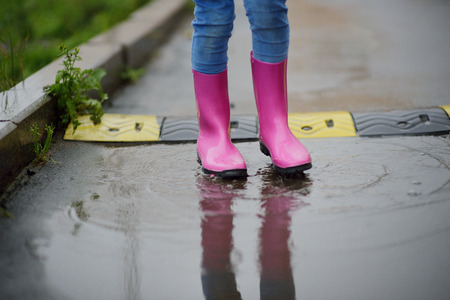 the childs legs in gumboots walk on poolsの写真素材