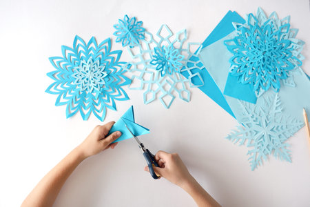 The child does snowflakes of blue paper.の写真素材