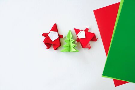 Santa Claus of origami a fir-tree of origami from paper on a white background. Hands of the child put a fir-tree.の写真素材
