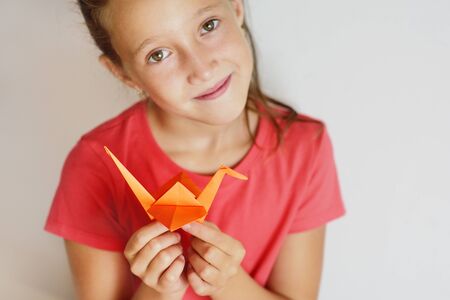 The girl puts origami from paper. Lesson of origamiの写真素材