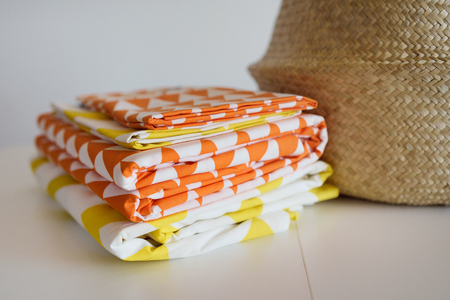 Bed multi-colored linen in a wicker basket against the background of a white wall on a white table.の写真素材