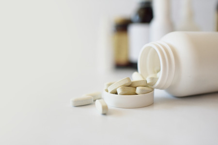 Vitamins, pills in a white plastic bottle on a white background. Against the background of drugsの写真素材