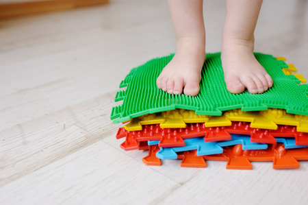 Legs of the child, the kid go on massage mats. Exercises for legs on orthopedic massage carpet.の写真素材