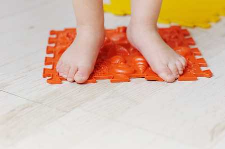 Legs of the child, the kid go on massage mats. Exercises for legs on orthopedic massage carpet.の写真素材