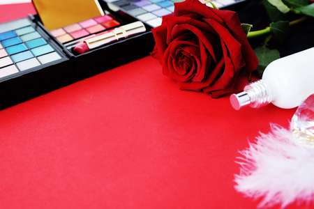 Valentines Day on a red background a red rose with jewelry, a bottle of  and cosmetics.の写真素材