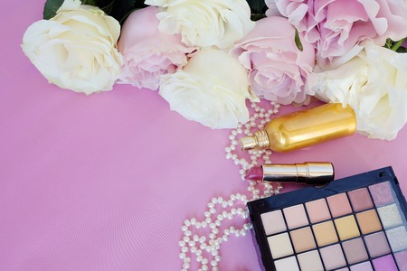 Valentine's Day. Female accessories, jewelry,  bottle, gift with ribbon , pearls, gentle roses on a pink background. Cosmetics. Top view.の写真素材