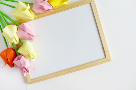 Paper tulips of origami on a white background, a wooden frameの写真素材