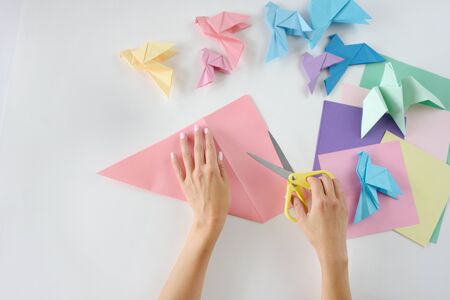 Children hands do origami from colored paper on white background. lesson of origamiの写真素材