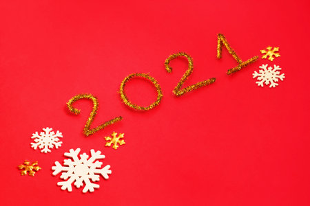 2021 number for New year greeting card. Christmas Party decoration on red background. Golden tinsel and snowflakesの写真素材