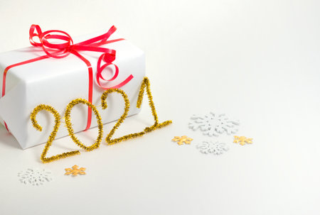 2021 number for New year greeting card. Christmas gift decoration on white background. Golden tinsel and snowflakes.の写真素材