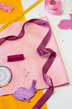 Easter craft bunny tutorial. Accessories for needlework. Tools and Equipment Thread, tape and fabric. Beads, scissors and pins on white background.の写真素材