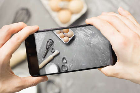 Female Hand with phone taking story with kitchen utensils for blog. Cook blogger filming video about accessories. Confectioner influenceの写真素材