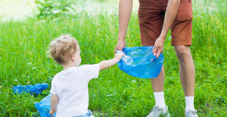 Boy is picking up plastic bottle. Man with his son cleaning outside , Young eco volunteer conceptの写真素材