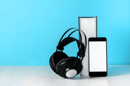 Headphones on book empty phone screen. Audiobook horizontal banner copyspace. Online education and e-learning conceptの写真素材