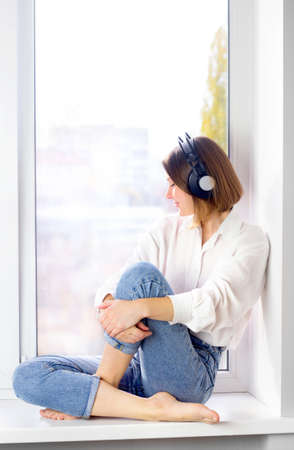 Relaxed young woman enjoying listening to music in wireless earphones at home, stress free meditation conceptの写真素材