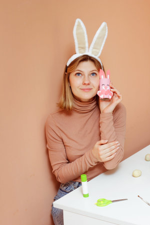 Beautiful young woman with bunny ears making Handmade Easter decoration little rabbit DIY. Reuse...